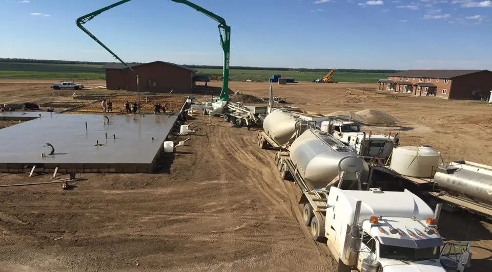 A cement truck is parked in the dirt.