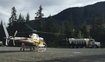 A helicopter is parked on the ground near some trees.